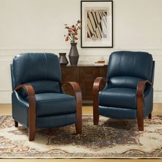 two blue leather chairs sitting on top of a rug