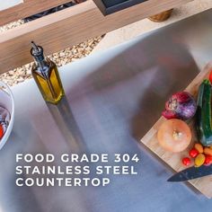 a stainless steel counter top with vegetables on it and a bottle of oil next to it