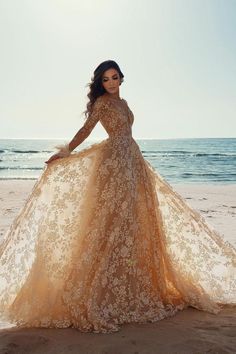 a woman standing on top of a beach next to the ocean wearing a long dress