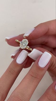 a woman's hand with white manies and a ring on her finger, holding a diamond