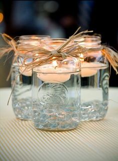 three mason jars filled with candles on top of a table