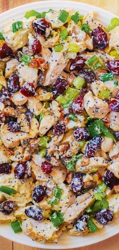 a white plate topped with chicken and cranberries on top of a wooden table