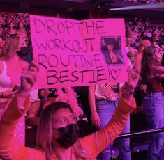 a woman wearing a face mask holds up a sign that reads drop the workout routine besties