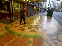 a man is walking down the sidewalk in front of a building with star designs painted on it