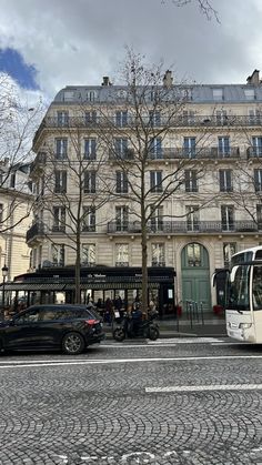 a white bus parked in front of a tall building on a cobblestone street