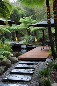 a wooden walkway in the middle of a garden with plants and rocks on either side