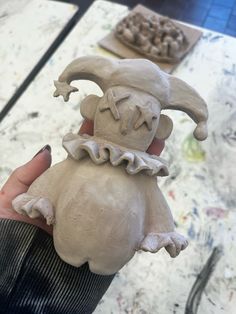 a hand holding a clay sculpture of an evil looking creature with its mouth open and eyes closed