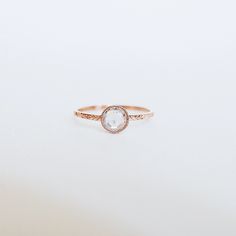 a rose gold ring with a white diamond in the center on a white background,