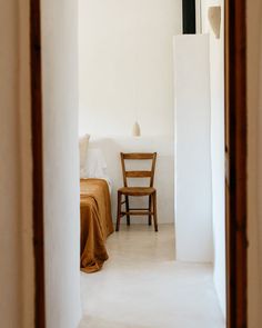 a chair sitting next to a bed in a room with white walls and flooring