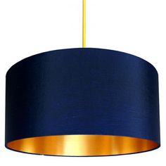 a blue and gold lamp shade hanging from a ceiling fixture with an orange strip at the end