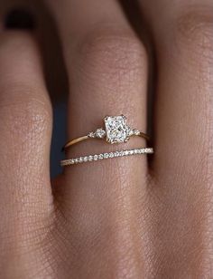 a woman's hand with a diamond ring on top of her finger and an engagement band