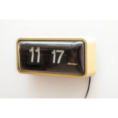 an alarm clock with the time 11 17 on it's face is shown against a white wall