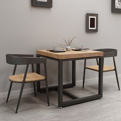 a dining table with two chairs next to it and pictures on the wall behind it