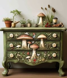 a green dresser with mushrooms painted on the side and plants growing out of it's drawers