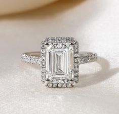 an emerald cut diamond ring with pave diamonds surrounding it