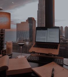 an open laptop computer sitting on top of a desk in front of a cityscape