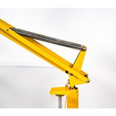 a close up of a yellow crane on a white wall