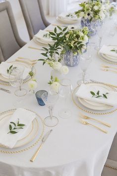 the table is set with white and gold place settings