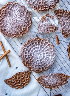 cookies are cooling on a wire rack with cinnamon sticks next to them and powdered sugar