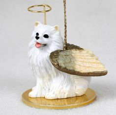 a small white dog holding a piece of bread on a plate with a keychain