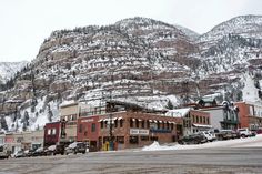 a town with mountains in the background and cars parked on the side of the road