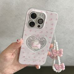 a person holding a cell phone case with an animal charm attached to the back of it