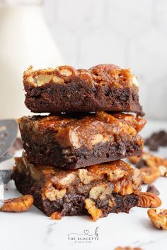 three brownies stacked on top of each other with pecans scattered around them and one piece cut in half