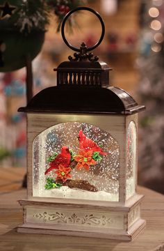 a lantern with flowers in it sitting on a table next to a christmas ornament