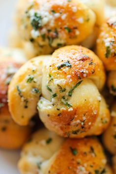 small rolls covered in cheese and herbs on top of a white plate with parmesan sprinkles