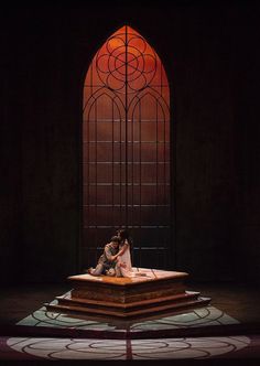 two people sitting on a platform in front of a stained glass window