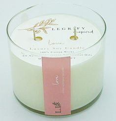 a white candle with a pink ribbon around it and a label on the front that says love