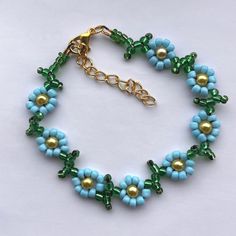 a blue and green beaded bracelet on a white surface with gold beads in the middle