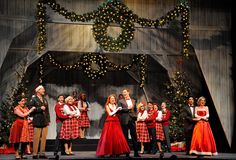 a group of people standing on top of a stage in front of christmas decorations and lights