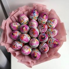 a bunch of decorated eggs sitting on top of a pink paper wrapper in a bouquet