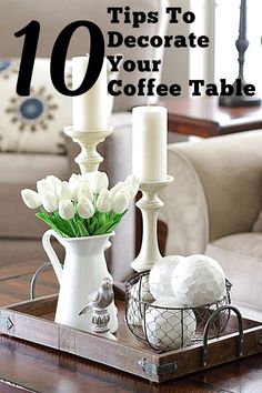 a tray with candles and flowers on it in front of a couch, coffee table