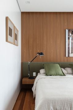 a bedroom with wood paneling and green pillows on the bed, along with two framed pictures