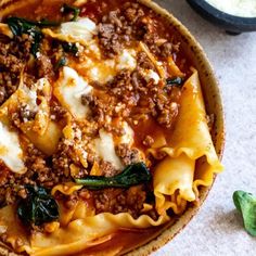 a bowl filled with pasta and meat covered in sauce