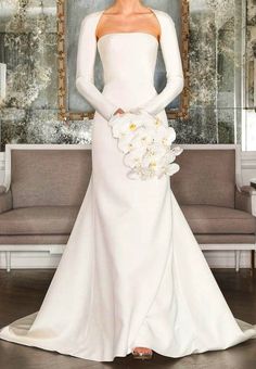 a woman in a white wedding dress standing next to a couch with flowers on it