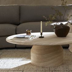 a living room with a couch, coffee table and vase on the floor in front of it