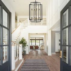 a large hallway with wooden floors and white walls, two chandeliers hanging from the ceiling