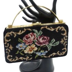 "La Regale Evening Bag Floral Needlepoint Kelly Style Purse This 1960's Evening Bag is Just Lovely. Done in a Small Size Kelly Bag Style this Beauty has a Gold Tone Metal Frame, Rounded Tube Carry Handle, and Working Hinged Latch Closure. The Bag is accented on the Front with Black Wool and Hand Stitched Floral Needlepoint in Pink, Burgundy, Purple, Red, Blue, Gold, Yellow, Green, Brown, and Tan. Inside the Bag is Lined in Black Silk and has One Open Pocket and a White Fabric La Regale Tag. The Back and Bottom of the Bag are done in Black Silk and are Not Decorated. 8\"W x 4 1/2\"H Condition: Excellent Clean inside and out. Hinged Latch Closure works. No holes. PU5245L-B66STR" Floral Needlepoint, Kelly Bag, + Core + Aesthetic, Green Brown, White Fabrics, Black Wool, Black Silk, Clutch Handbag, Gold Tone Metal