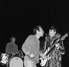 two men playing guitars and singing into microphones