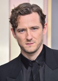 a close up of a person wearing a suit and tie with a serious look on his face