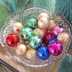 a glass bowl filled with christmas ornaments on top of a table