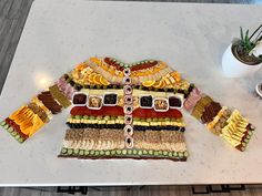 a table topped with a cake covered in fruit and vegtables next to a potted plant