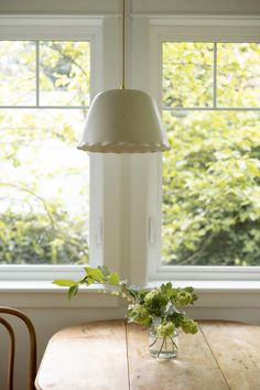 a wooden table sitting under a window next to a vase with flowers on top of it