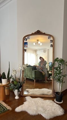 a mirror sitting on top of a wooden table next to a plant and potted plants