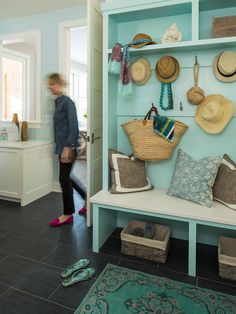 a woman walking past a blue shelf with hats on it and other items hanging on the wall