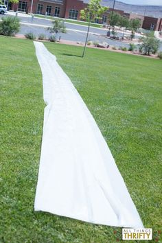 a long white sheet laying on top of a lush green field