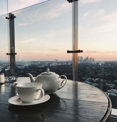 two cups and saucers sit on a table overlooking the city